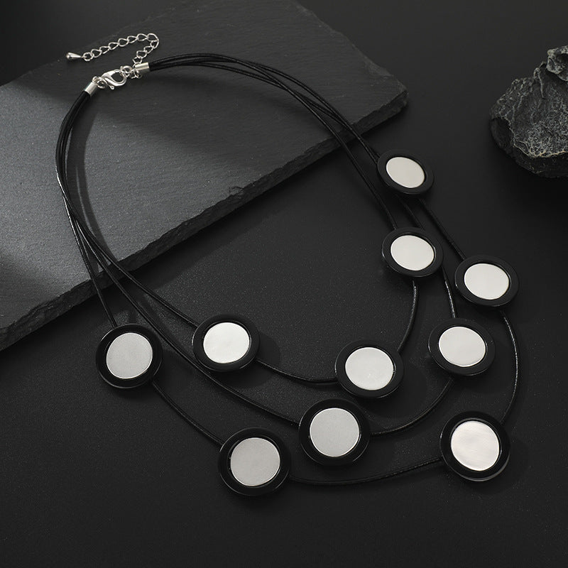 Elegant black multi-layered necklace with circular mirror accents. A bold statement piece for women’s fashion jewelry