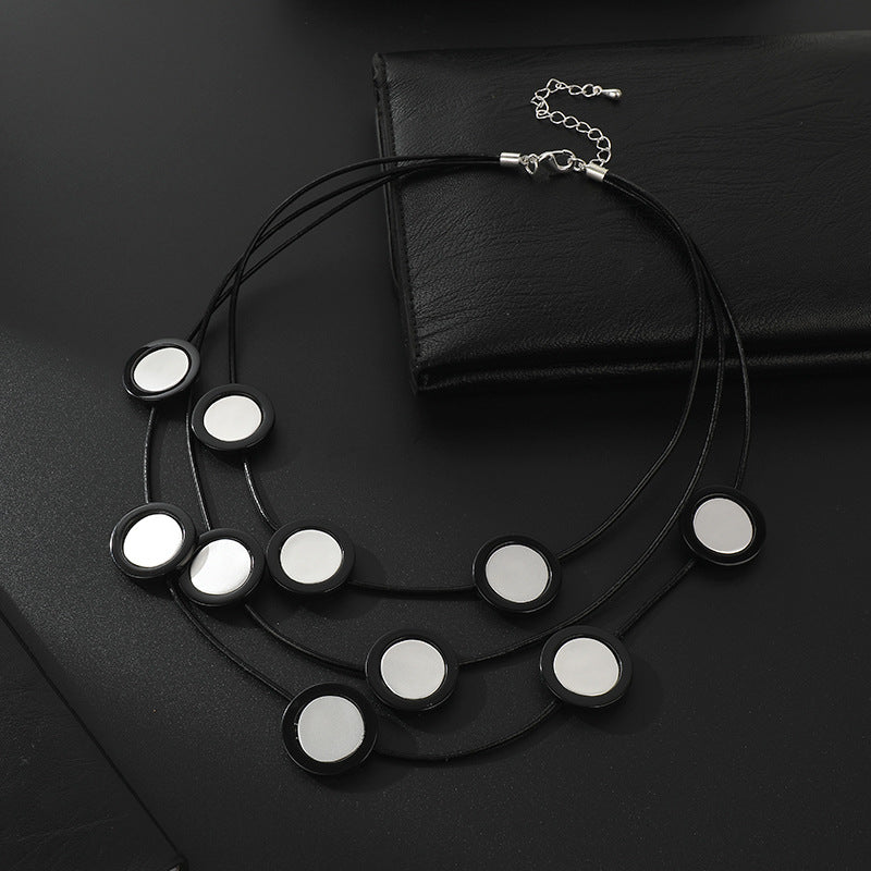 Elegant black multi-layered necklace with circular mirror accents. A bold statement piece for women’s fashion jewelry