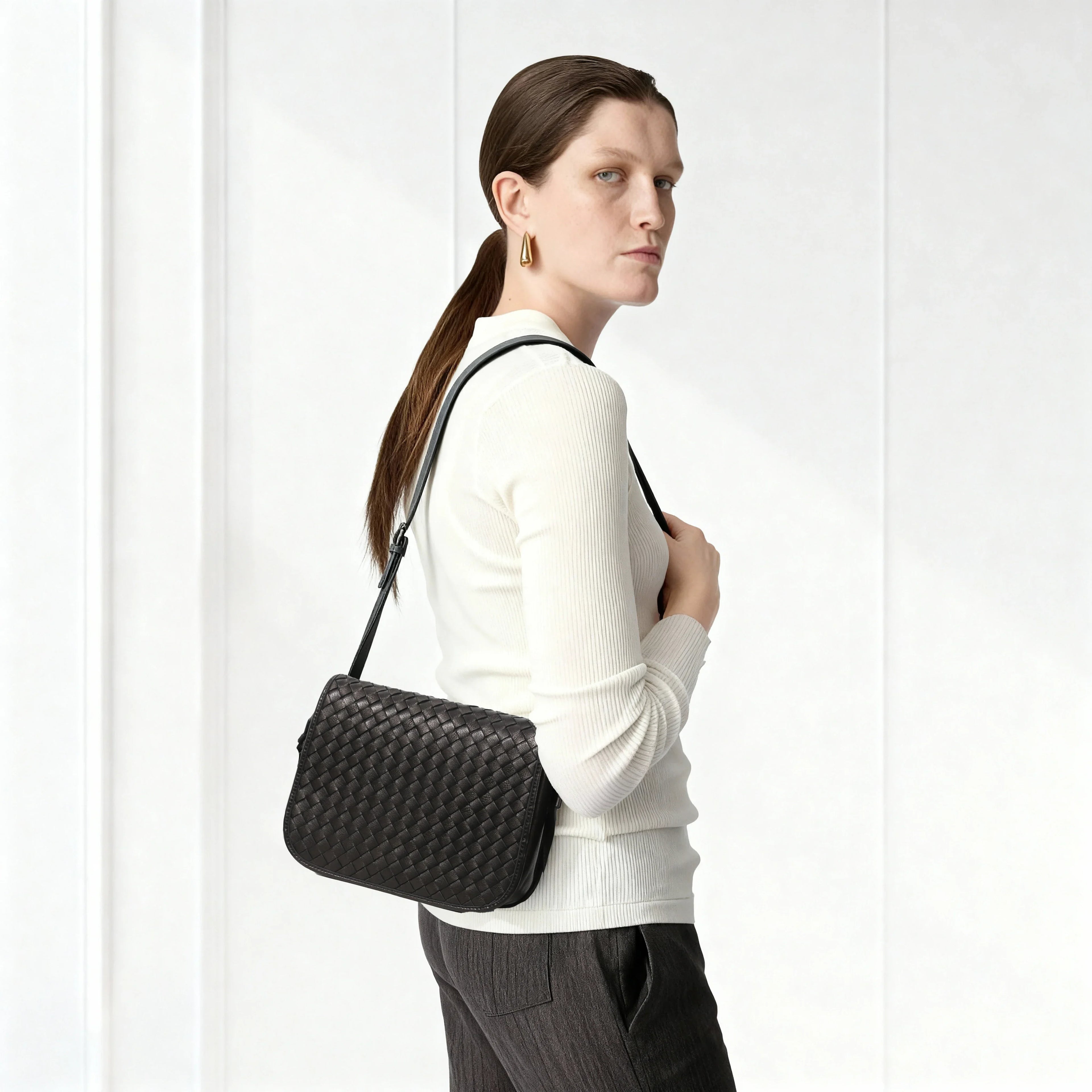 Woman carrying a black woven handbag against a white background