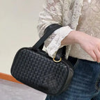 Side view of black braided leather handbag with structured silhouette and soft lambskin texture