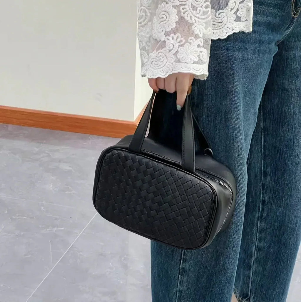 Woman holding black woven leather tote bag – elegant minimalist style for everyday use
↳