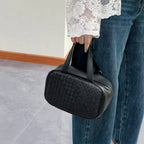 Woman holding black woven leather tote bag – elegant minimalist style for everyday use
↳