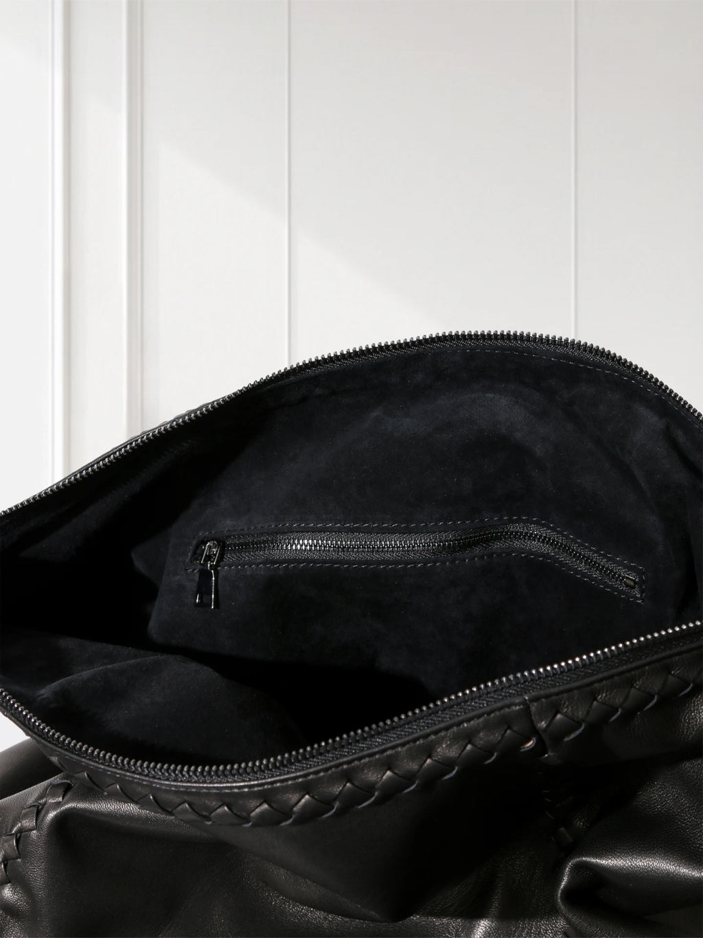 Close-up of a black leather bag with braided handle on a white background