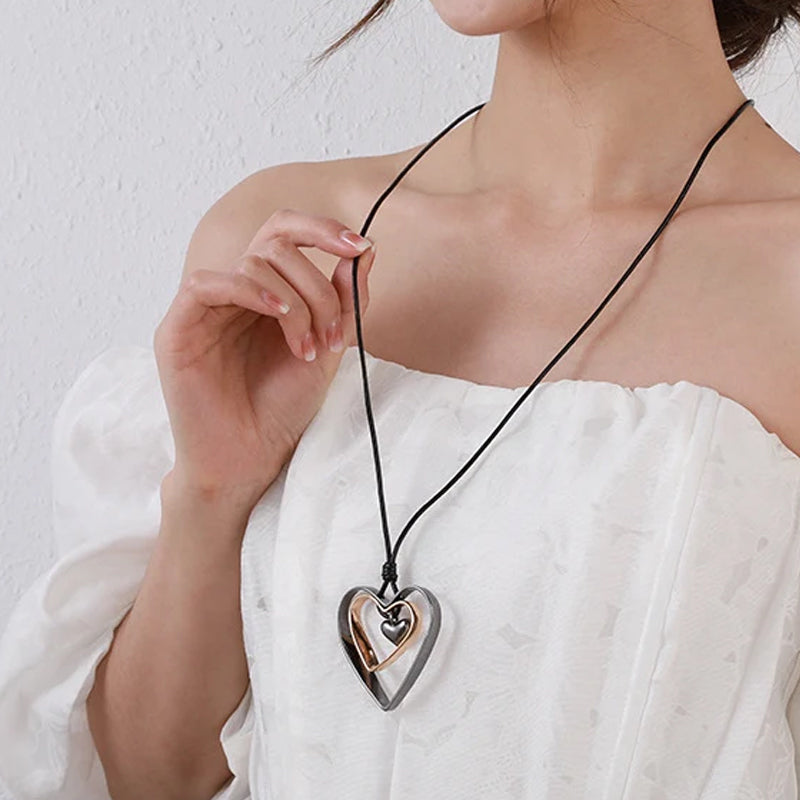 Person wearing a necklace with a heart-shaped pendant on a white background