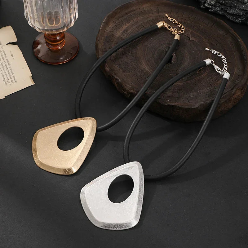 Two necklaces with geometric pendants on a dark surface.