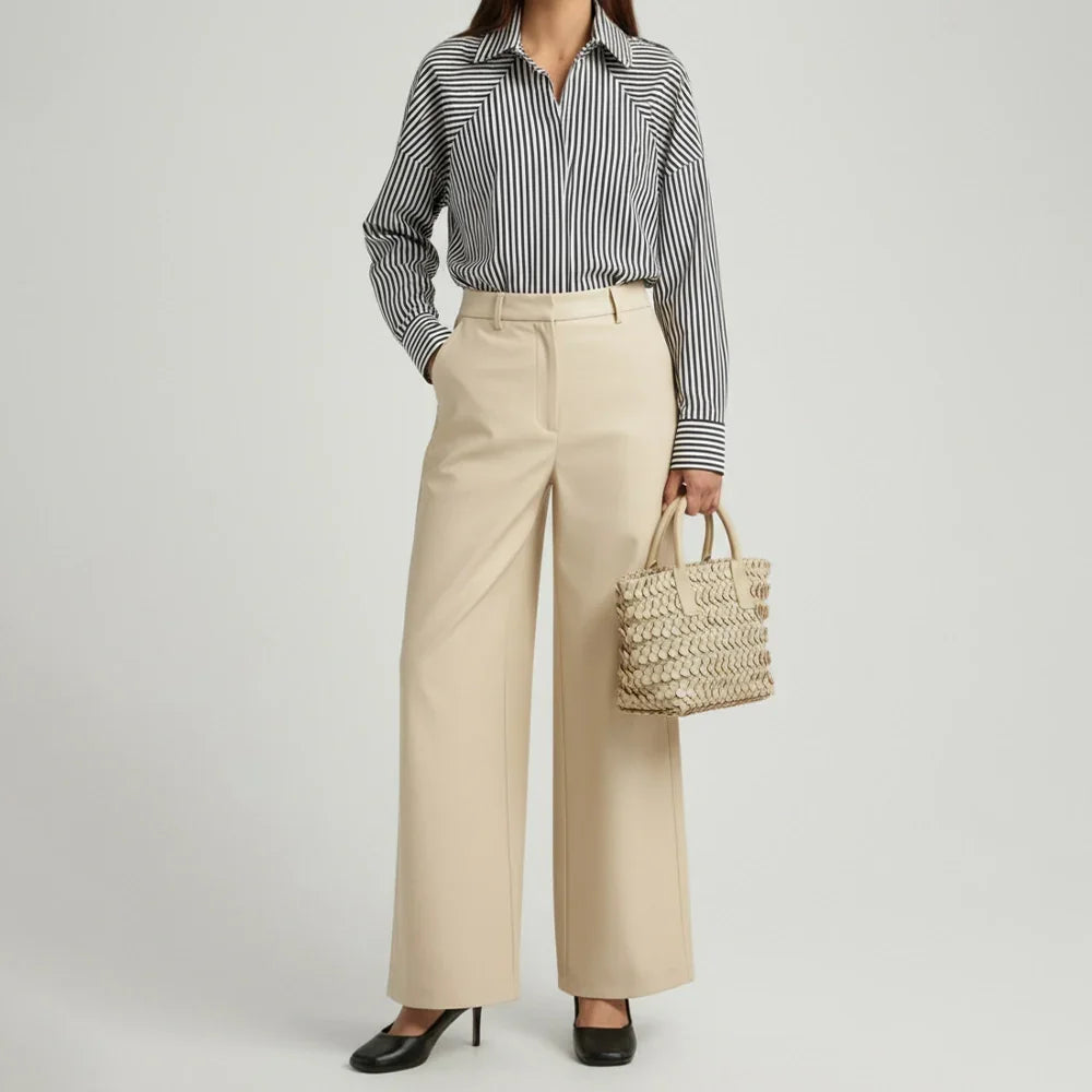 CREAM leather tote bag with circular appliqué design, placed on a decorative white pedestal.