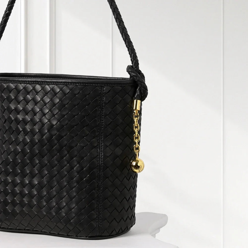 Elegant handwoven leather bucket bag in brown and blue tones with braided shoulder strap and gold-tone accents