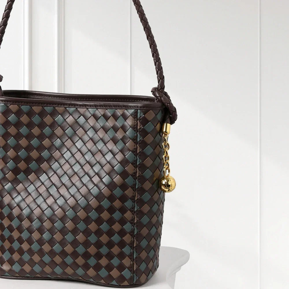 Elegant handwoven leather bucket bag in brown and blue tones with braided shoulder strap and gold-tone accents