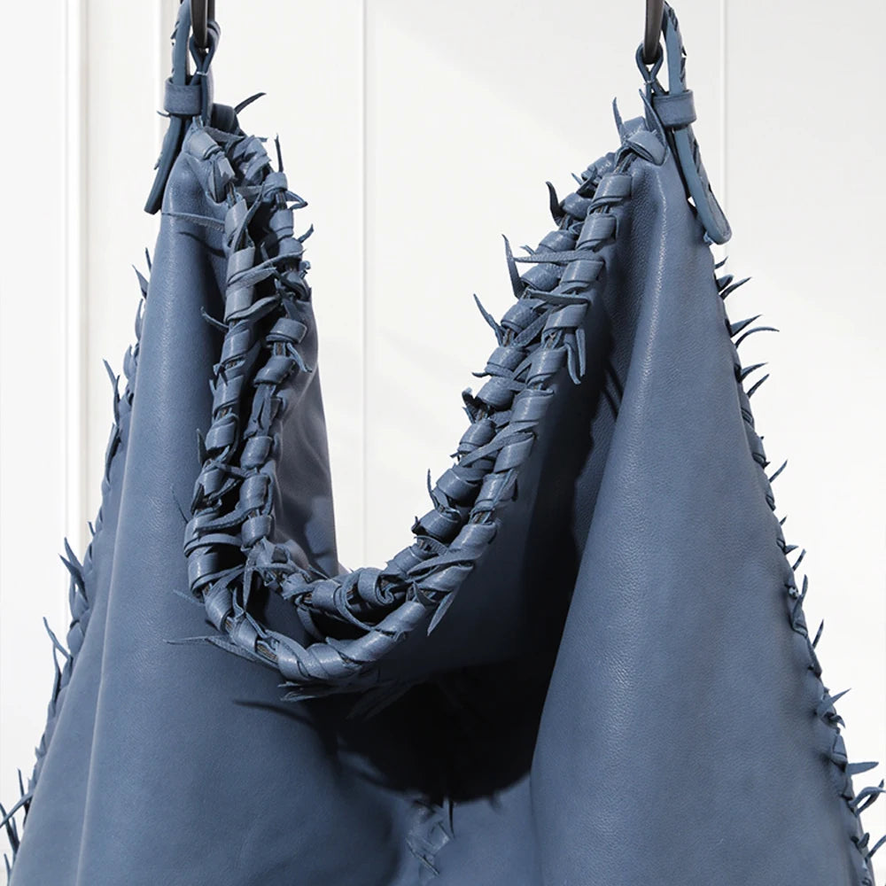 Gray leather bag with decorative elements on a white background