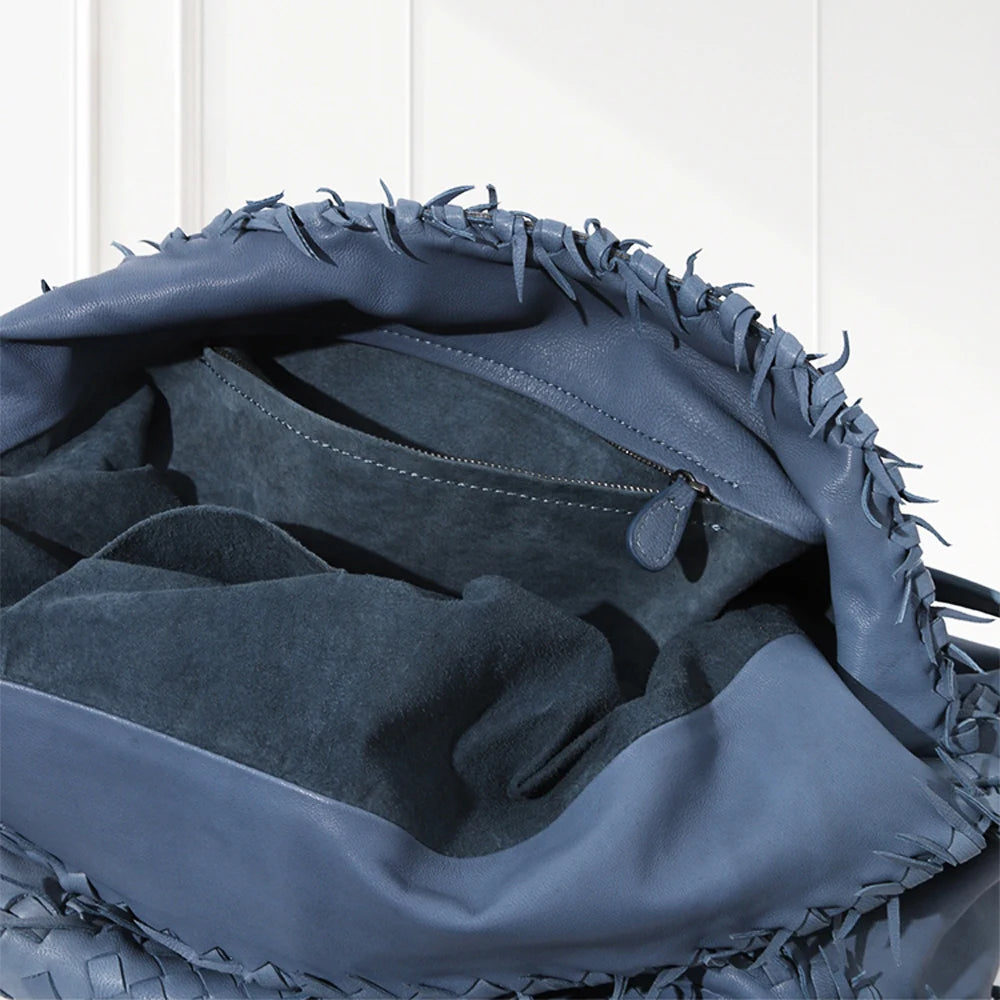 Close-up of a blue leather bag with textured surface and visible stitching on a white background