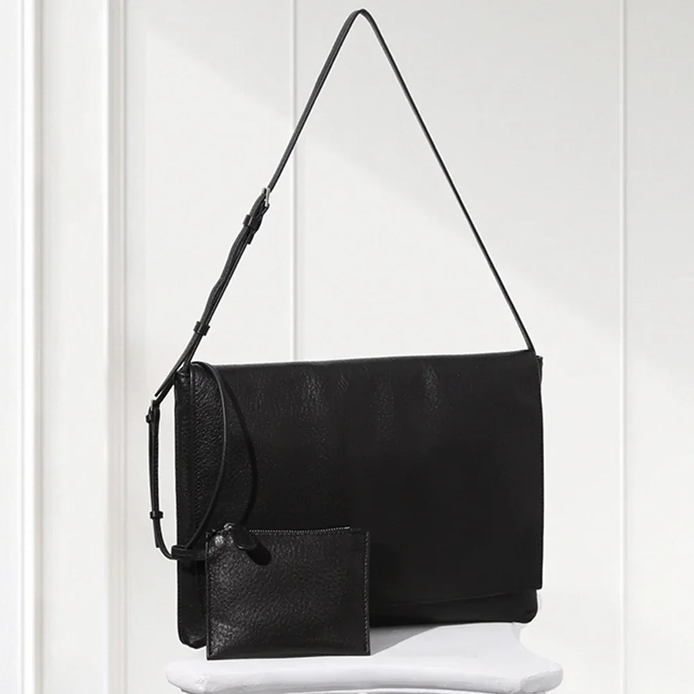 Black leather handbag with matching wallet on a white surface