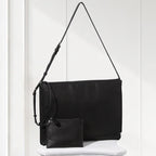 Black leather handbag with matching wallet on a white surface