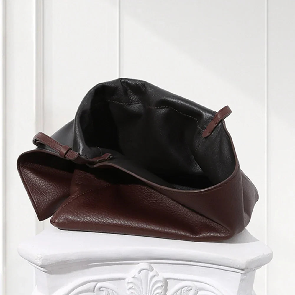 Minimalist dark brown lambskin messenger bag with front flap, adjustable shoulder strap, and slim rectangular design for women.