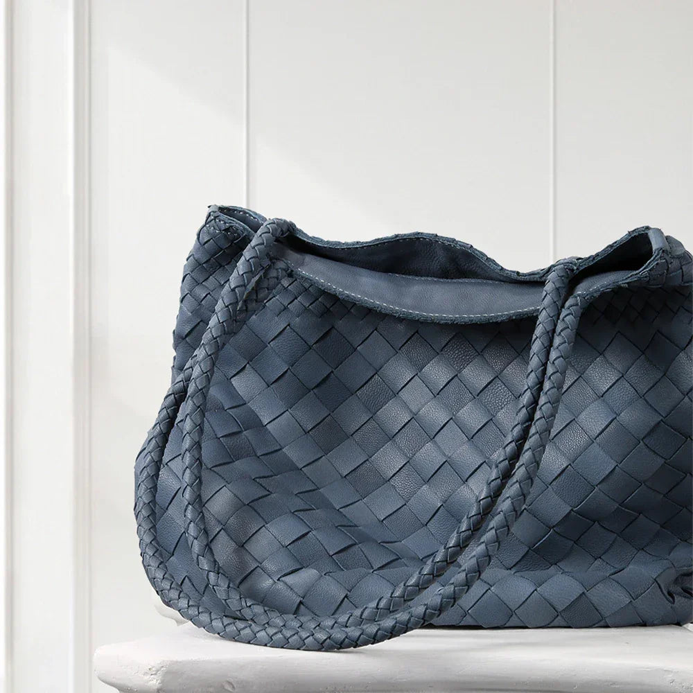 Blue woven handbag on a white surface with a light gray background