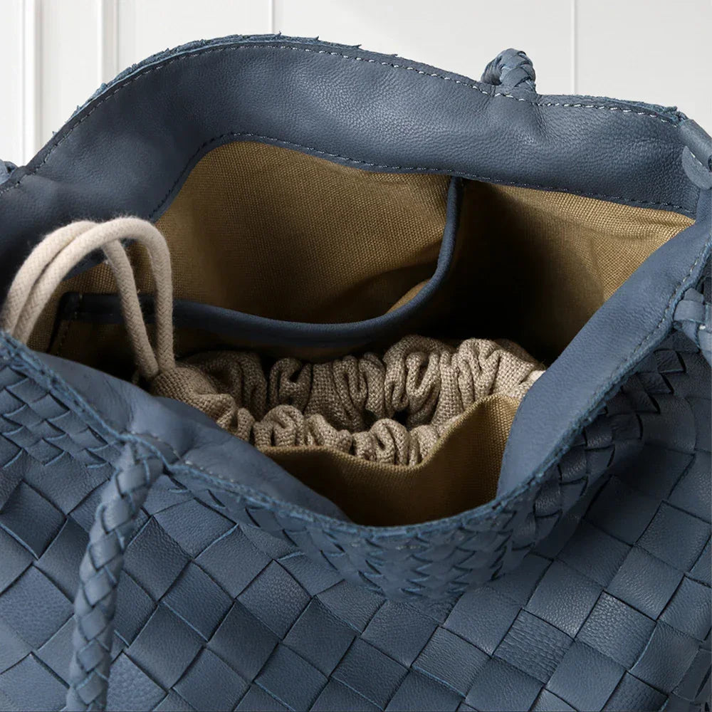 Blue woven handbag with a beige interior and braided handle.