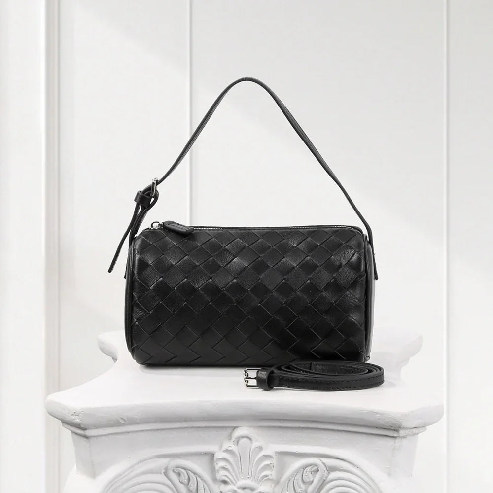 Side view of elegant black woven leather handbag, handcrafted weave design with smooth finish.