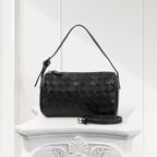 Side view of elegant black woven leather handbag, handcrafted weave design with smooth finish.