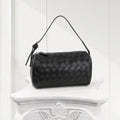 Front view of black woven leather handbag with structured top handle, luxury women’s shoulder bag.