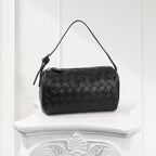 Front view of black woven leather handbag with structured top handle, luxury women’s shoulder bag.