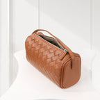 Brown woven handbag with a zipper on a white background