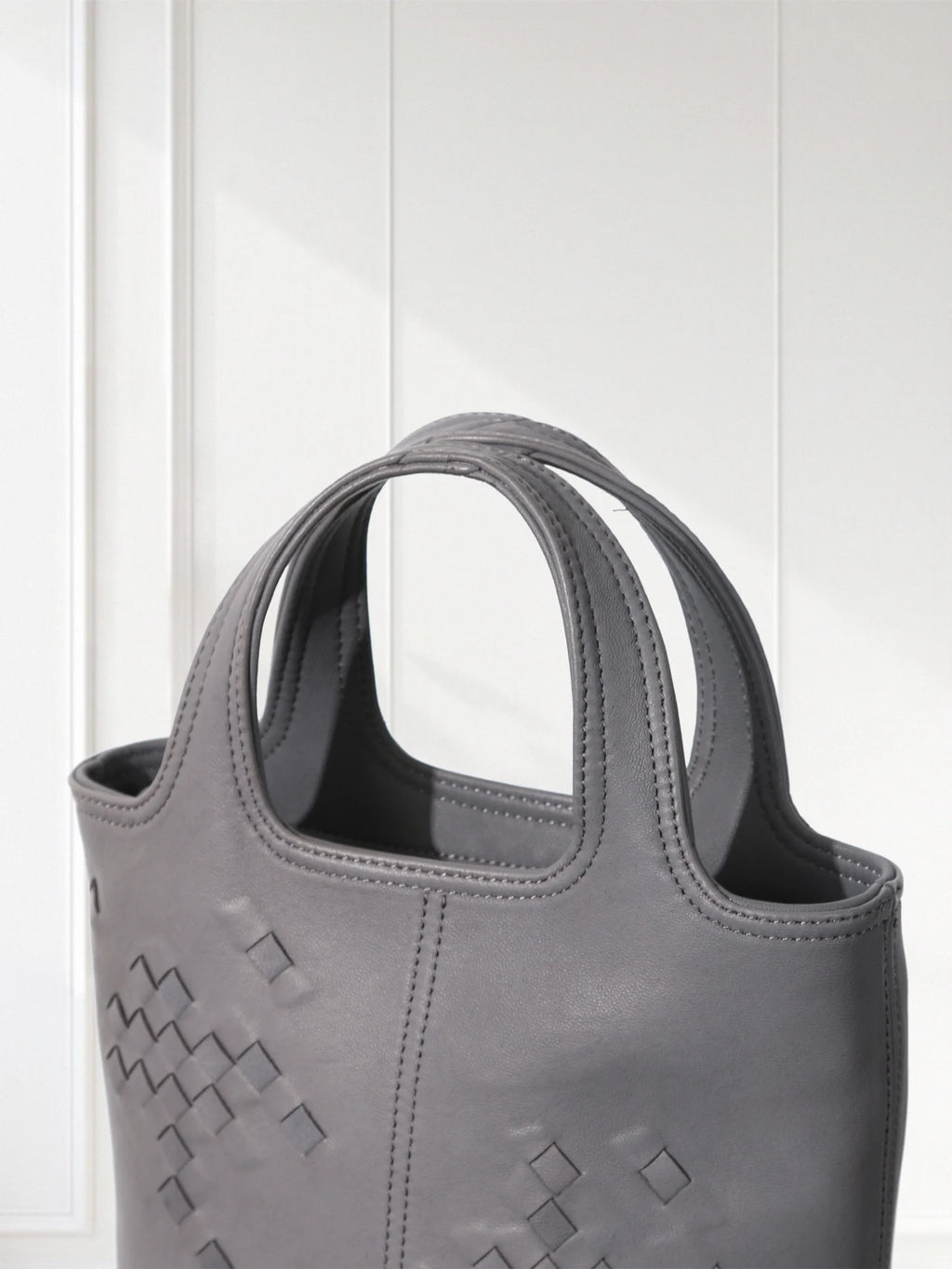 Gray handbag with geometric pattern on a white background