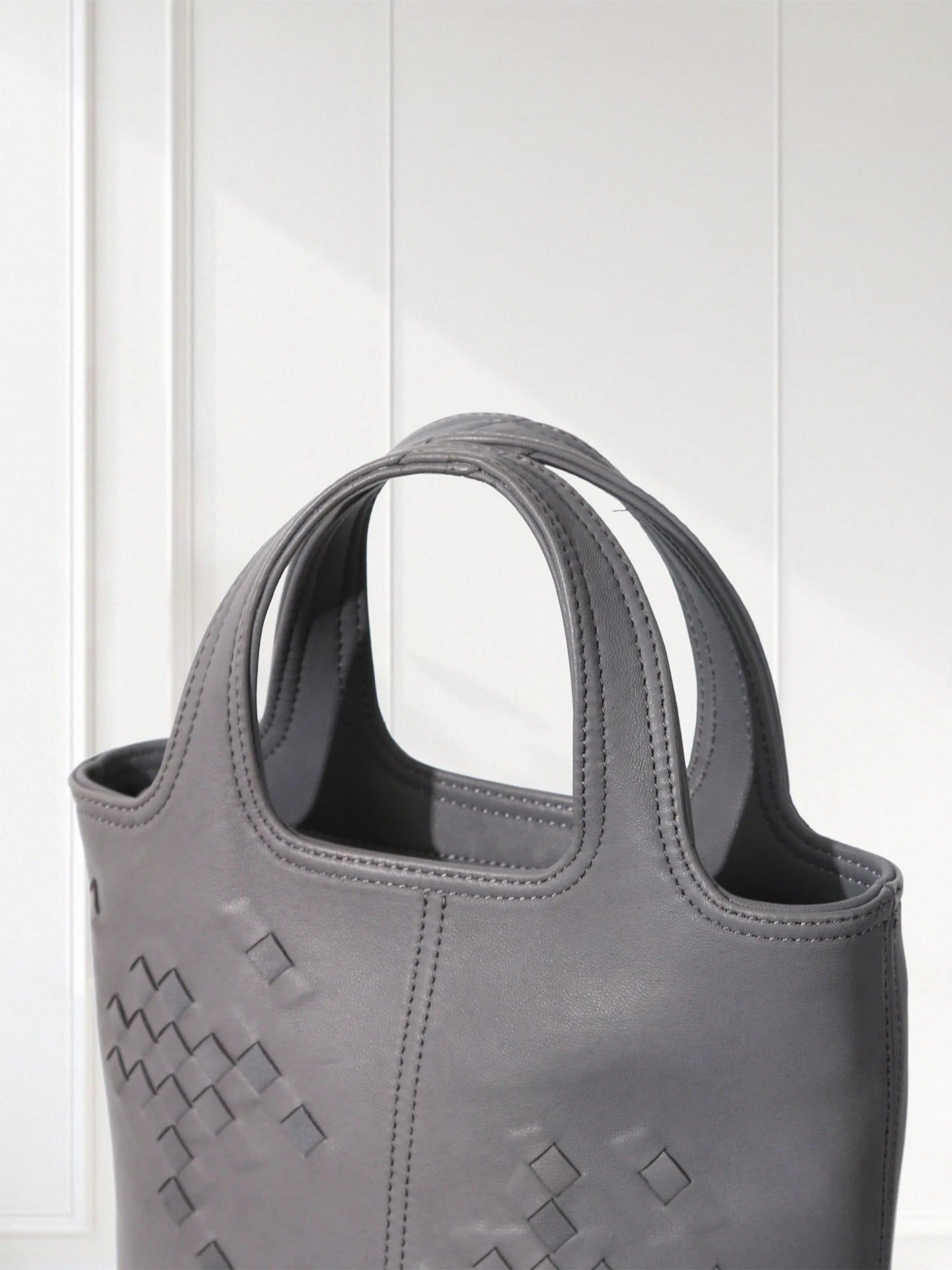 Gray handbag with geometric pattern on a white background