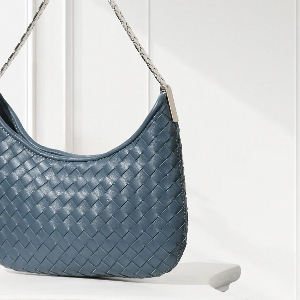 Blue woven handbag with a chain strap on a white surface