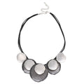 A statement necklace featuring five organic-shaped, textured silver discs layered over a multi-strand black cord, with a silver chain clasp at the top, shown on a plain white background.