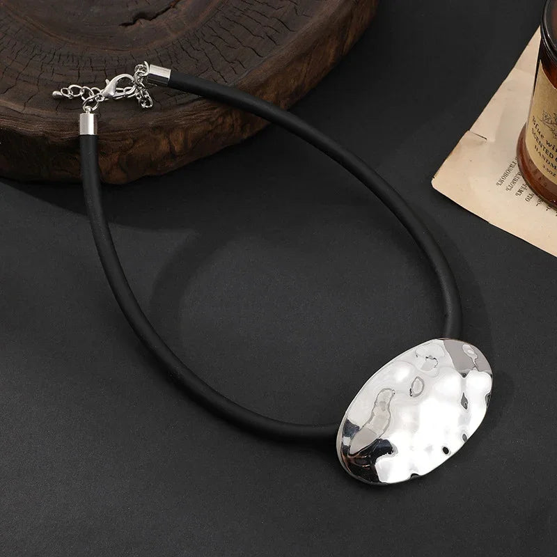 Textured silver oval pendant on black rubber cord, abstract modern jewelry design | Shop Civibuy near New York