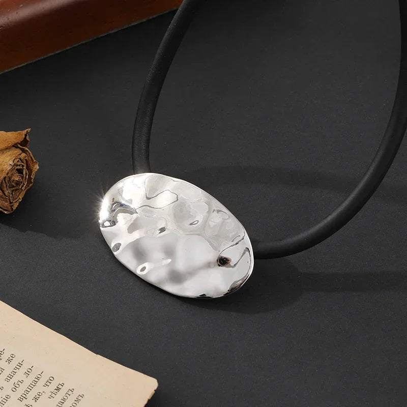 Textured silver oval pendant on black rubber cord, abstract modern jewelry design | Shop Civibuy near New York