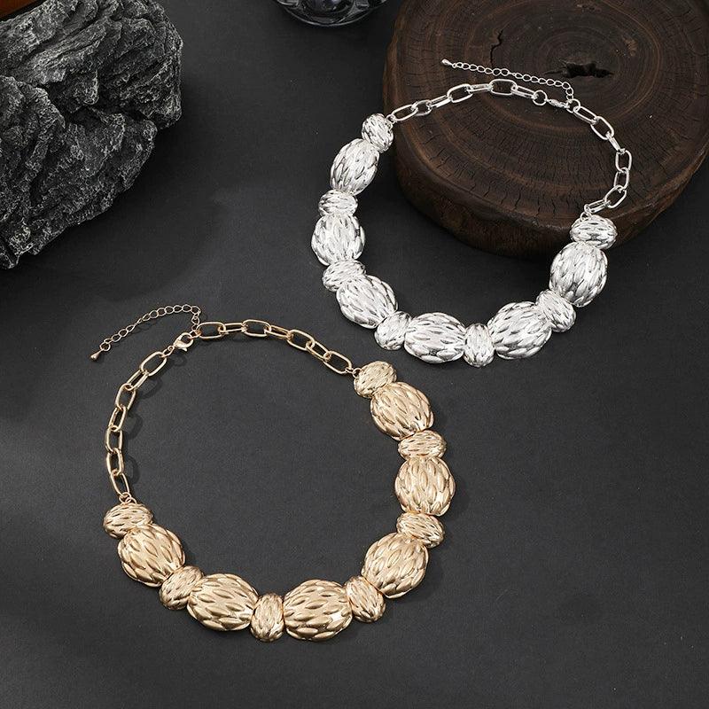 Two gold and silver necklaces on a dark surface