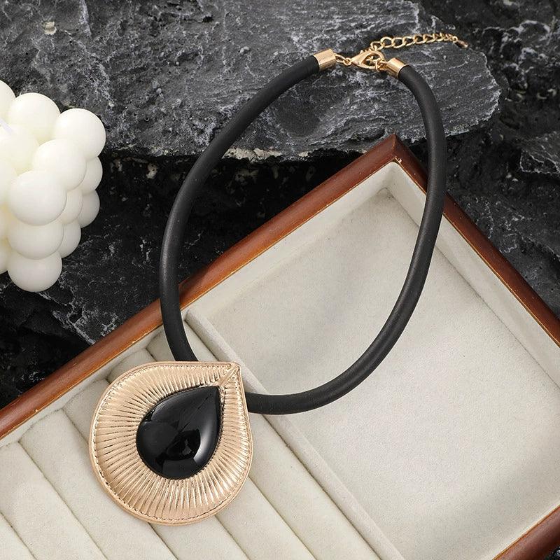 Necklace with black pendant and gold accents on a textured surface