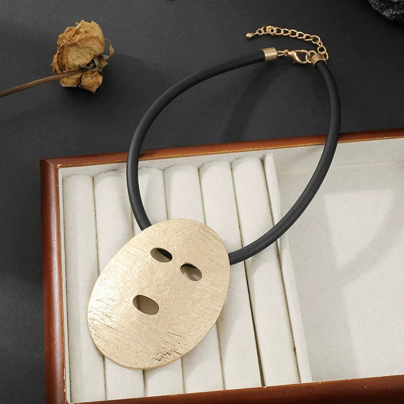 Necklace with a gold pendant on a black cord in an open jewelry box.