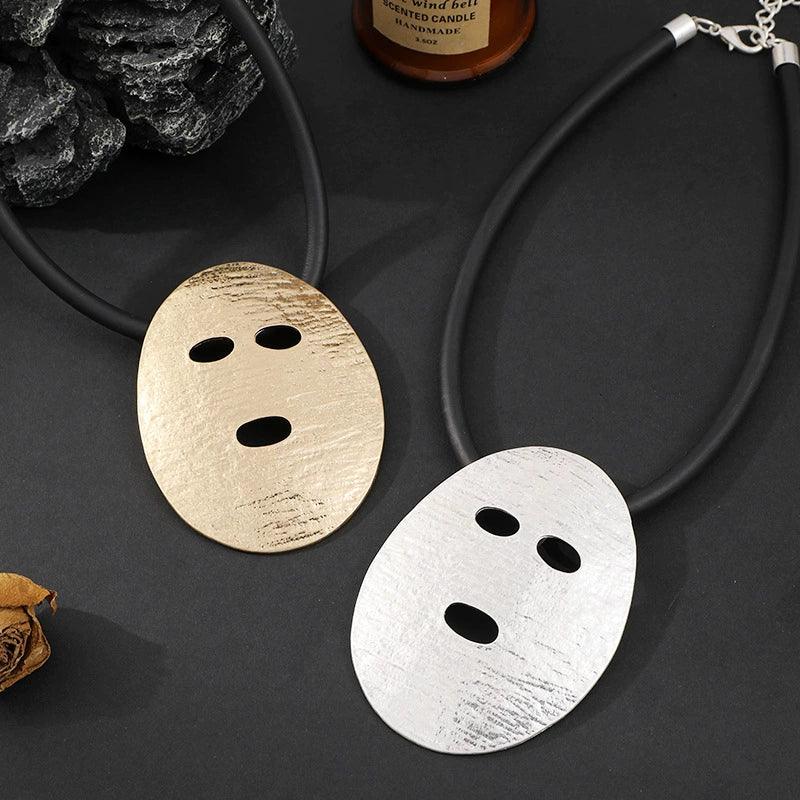 Two metallic pendants on a dark surface with a necklace.