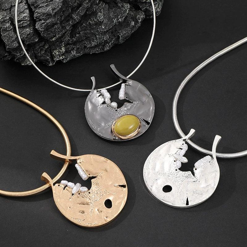 Three unique necklaces with different designs on a dark surface