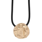 Gold pendant necklace on a black cord against a white background