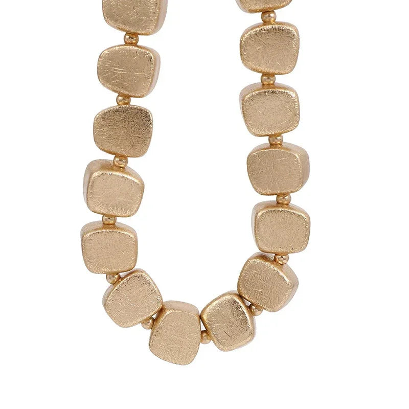 Gold necklace with square beads on a white background