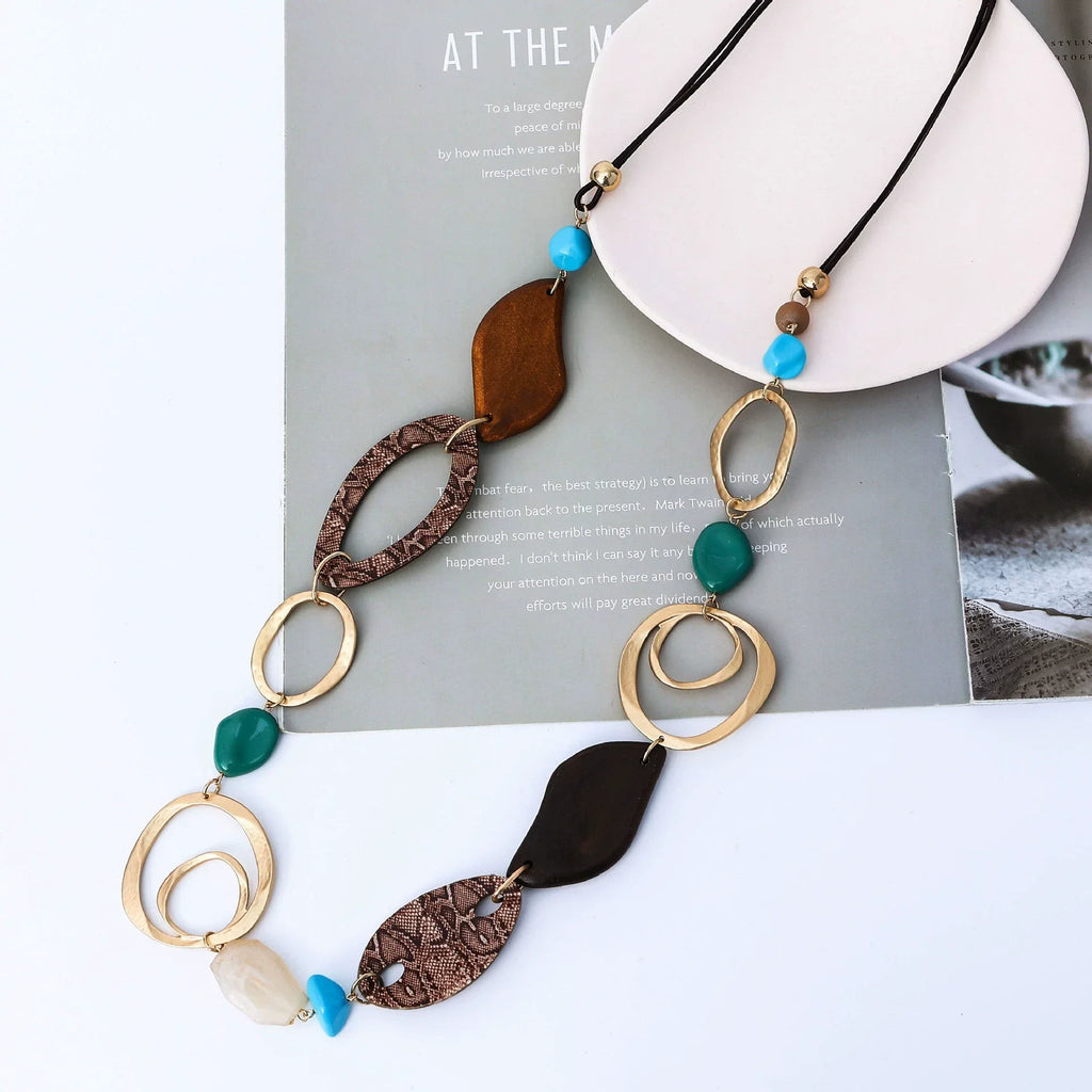 Necklace with brown, green, and gold elements on a magazine page Wholesale available near CA, US on Civibuy.com.