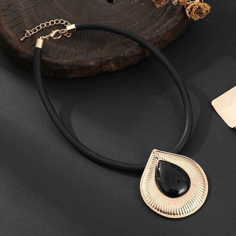 Black necklace with a gold pendant on a dark surface