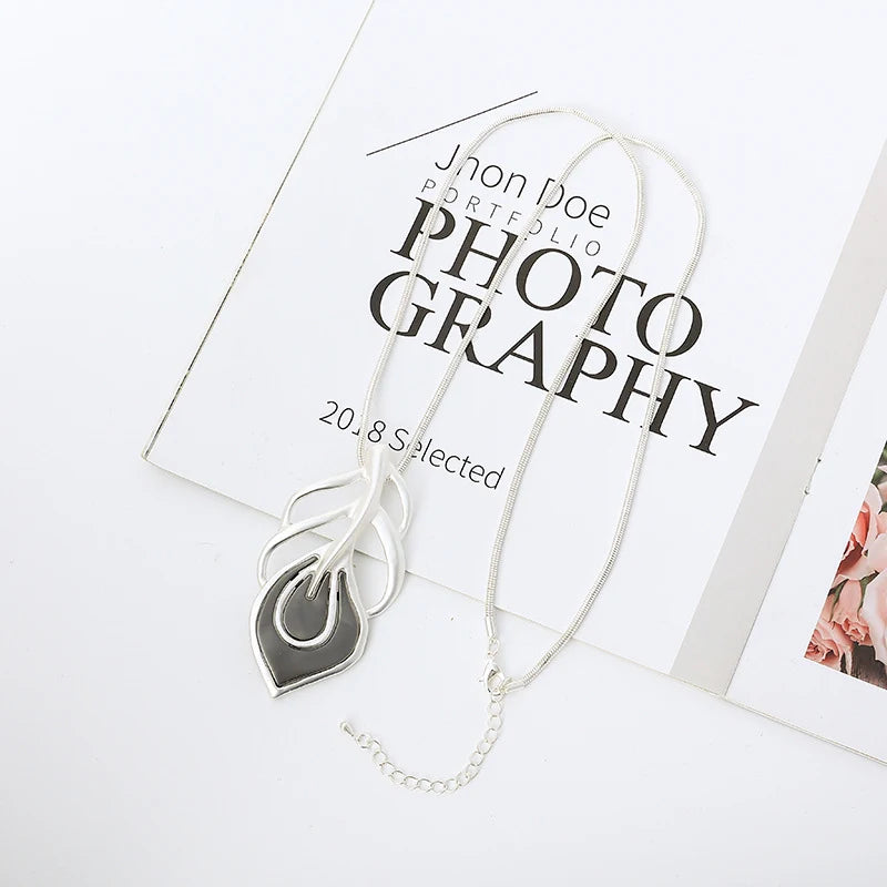 Silver necklace with a leaf-shaped pendant on a photography portfolio background
