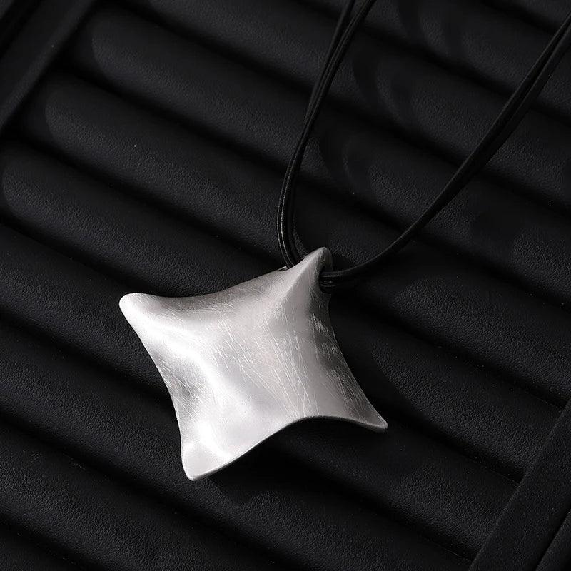 Silver pendant on a black cord against a black background