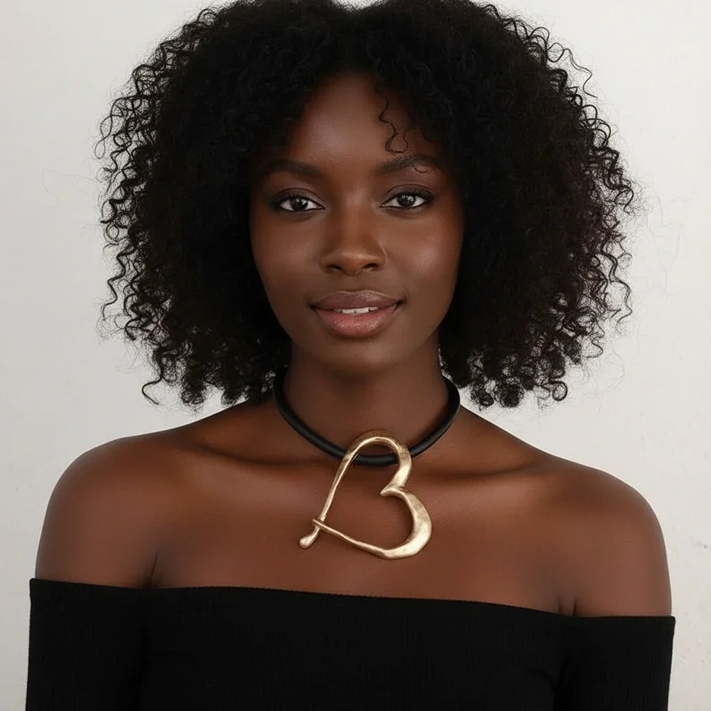 Woman wearing a gold necklace with a 'B' design against a plain background