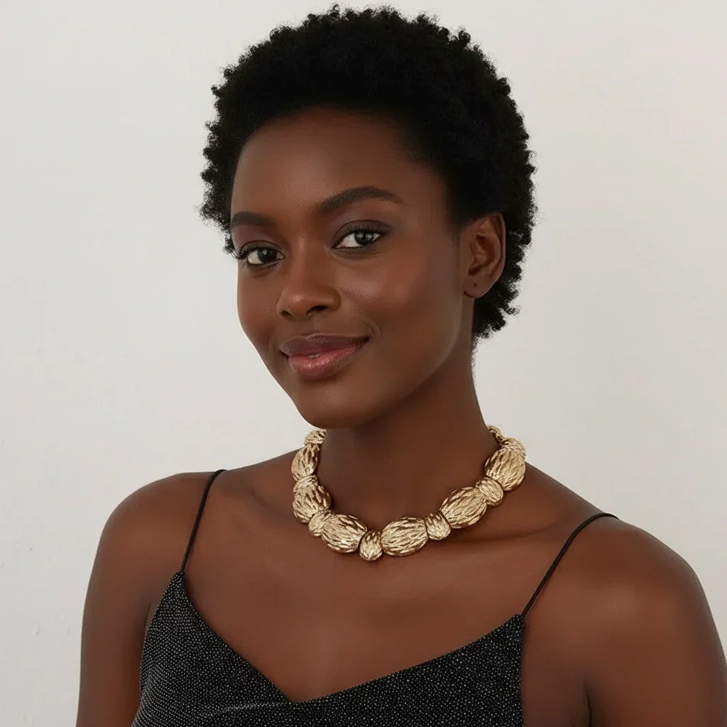 Woman wearing a gold necklace against a plain background