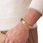 Gold bracelet on a wrist with a neutral background