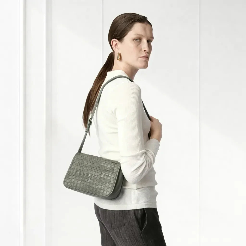 Woman carrying a green textured handbag against a white background
